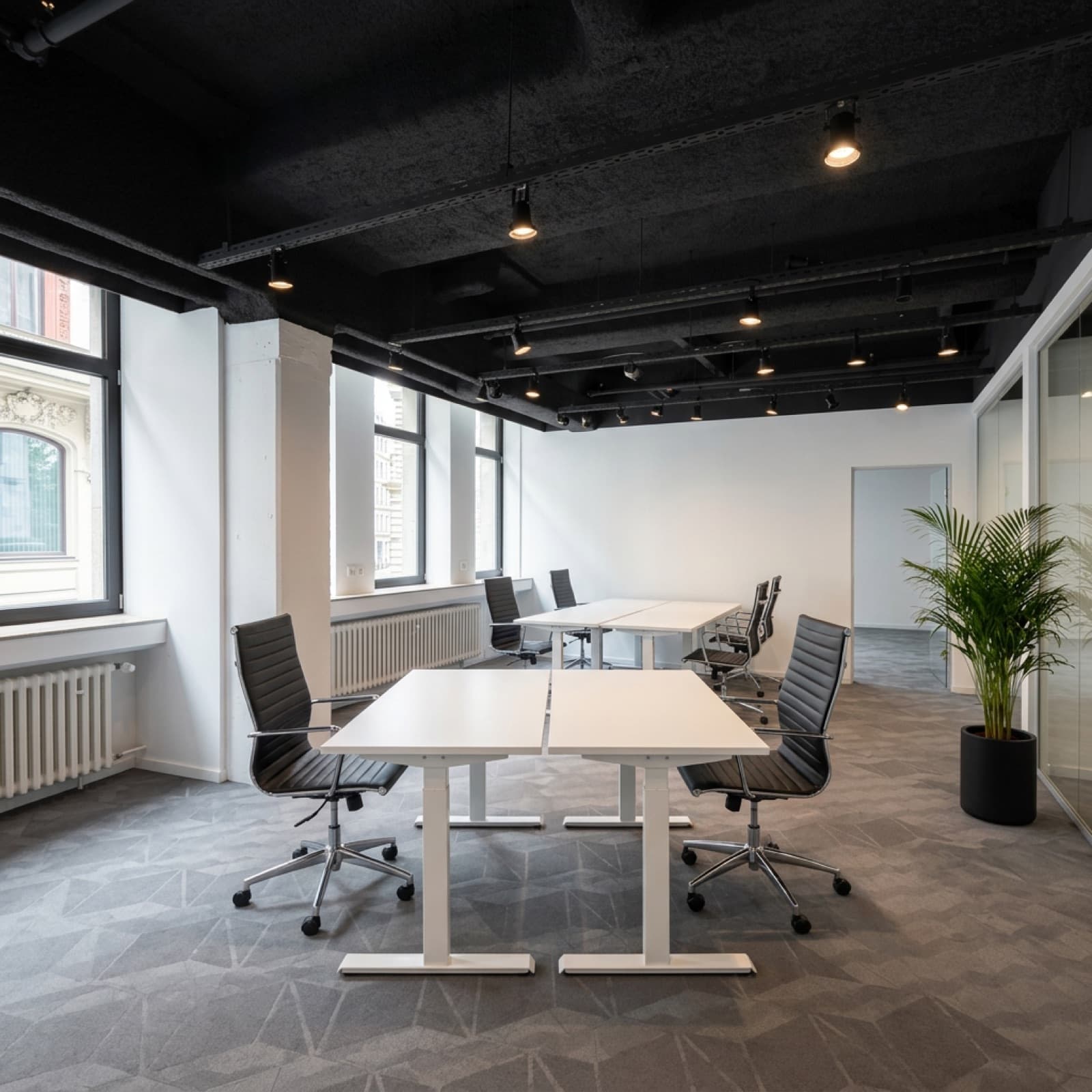 Leeres Büro mit weißen Schreibtischen und Blick auf die Nachbarfassade