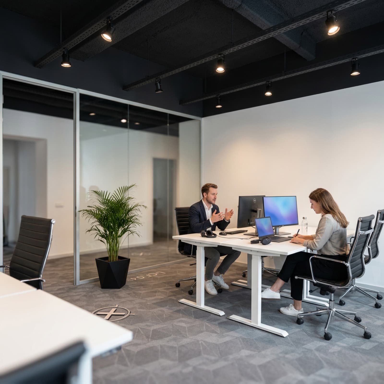 Abgeschlossenes Büro für zwei Personen mit Glaswand und Monitorarbeitsplätzen